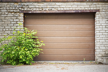 Image showing Garage wooden plank door, dirty grunge brick wall