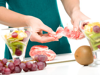 Image showing Cook is peeling grapefruit for fruit dessert