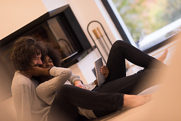 Image showing multiethnic couple using tablet computer on the floor