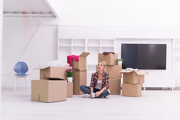 Image showing woman with many cardboard boxes sitting on floor