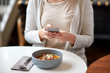 Image showing woman with smartphone and pumpkin soup at cafe