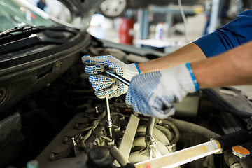 Image showing mechanic man with wrench repairing car at workshop