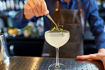 Image showing bartender decorating glass of cocktail at bar