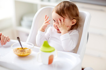 Image showing baby sitting in highchair and eating at home