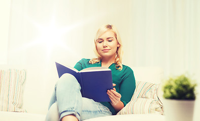 Image showing smiling woman reading book at home