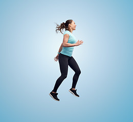 Image showing happy smiling sporty young woman jumping in air