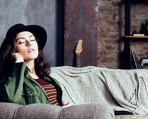 Image showing young pretty woman waiting alone in modern loft studio, hipster in hat, fashion musician concept, lifestyle people 