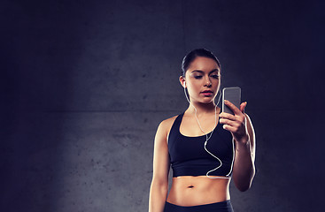 Image showing woman with smartphone and earphones in gym