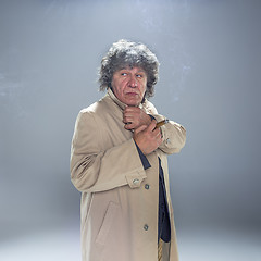 Image showing The senior man with cigar as detective or boss of mafia on gray studio background