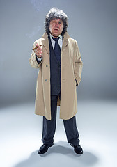 Image showing The senior man with cigar as detective or boss of mafia on gray studio background