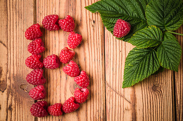 Image showing Letter B of raspberries with leaves on a wooden surface, close-u