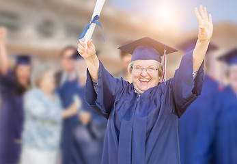 Image showing Happy Senior Adult Woman In Cap and Gown At Outdoor Graduation C