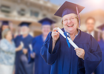 Image showing Happy Senior Adult Woman In Cap and Gown At Outdoor Graduation C