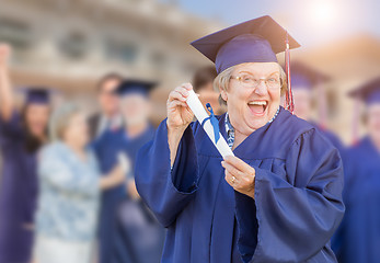 Image showing Happy Senior Adult Woman In Cap and Gown At Outdoor Graduation C