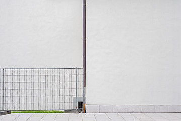 Image showing white wall with water pipe, metal security fence