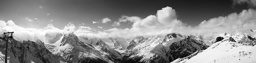 Image showing Black and white panoramic view on ski slope and cloudy mountains