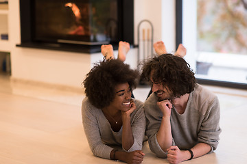 Image showing multiethnic couple lying on the floor  in front of fireplace