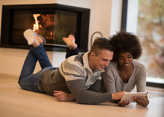 Image showing multiethnic couple using tablet computer on the floor