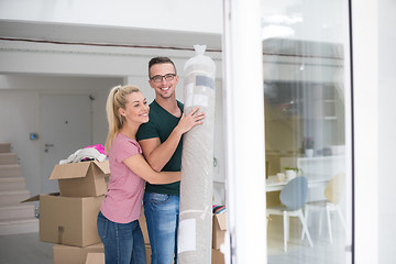 Image showing couple carrying a carpet moving in to new home