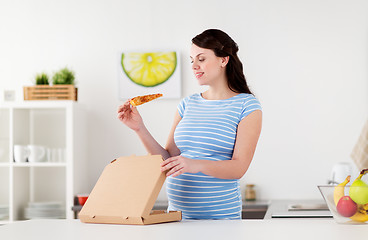 Image showing happy pregnant woman eating pizza at home kitchen