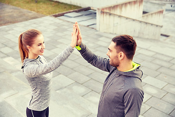 Image showing smiling couple making high five on city street