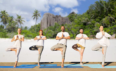 Image showing people making yoga in tree pose on mats outdoors