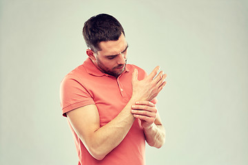 Image showing unhappy man suffering from pain in hand