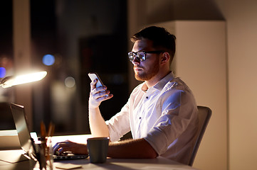 Image showing businessman texting on smartphone at night office