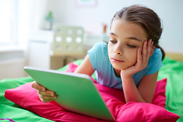 Image showing smiling girl with tablet pc lying in bed at home