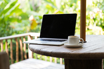 Image showing coffee cup and laptop computer on table outdoors