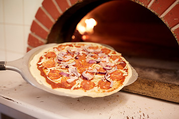 Image showing peel placing pizza into oven at pizzeria