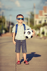 Image showing Caucasian little boy standing on the road and holding his soccer