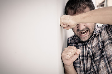 Image showing portrait one sad man standing near a wall and covers his face