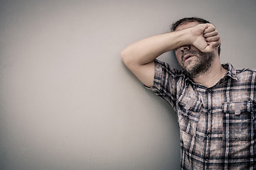 Image showing portrait one sad man standing near a wall and covers his face