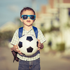 Image showing Caucasian little boy standing on the road and holding his soccer