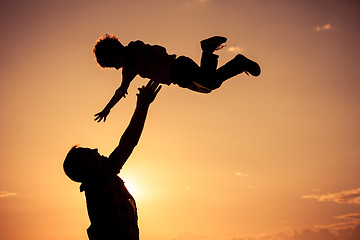 Image showing Father and son playing on the beach at the sunset time.