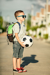 Image showing Caucasian little boy standing on the road and holding his soccer