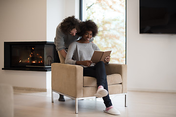 Image showing multiethnic couple hugging in front of fireplace