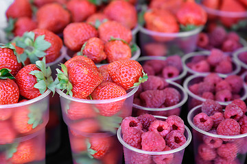 Image showing Raspberries and strawberries in containers for sale.