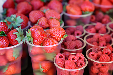 Image showing Raspberries and strawberries in containers for sale.