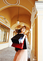 Image showing young pretty smiling woman in hat with bags on shopping at store