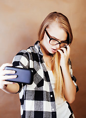 Image showing young pretty blond hipster girl making selfie on warm brown back