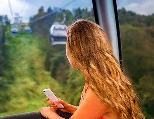 Image showing The girl in the cabin cable car in the mountains.