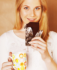 Image showing young cute blond girl eating chocolate and drinking coffee close