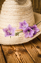 Image showing Straw hat and flowering campanula, close-up