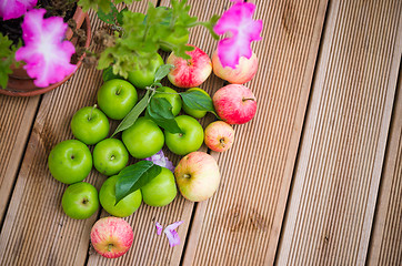 Image showing Ripe apples with a leaf on a wooden surface, top view