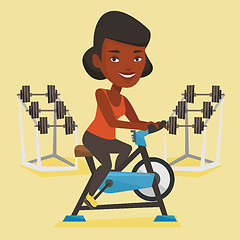 Image showing Young woman riding stationary bicycle.