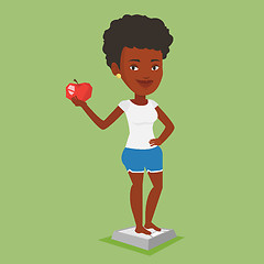 Image showing Woman standing on scale and holding apple in hand.