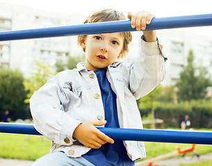 Image showing little cute boy playing on playground, hanging on gymnastic ring