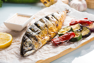 Image showing fish baked on the grill. with potatoes and lemon. 